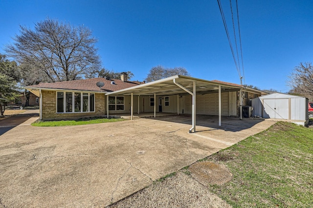 back of property with an outbuilding, a garage, brick siding, a carport, and a shed