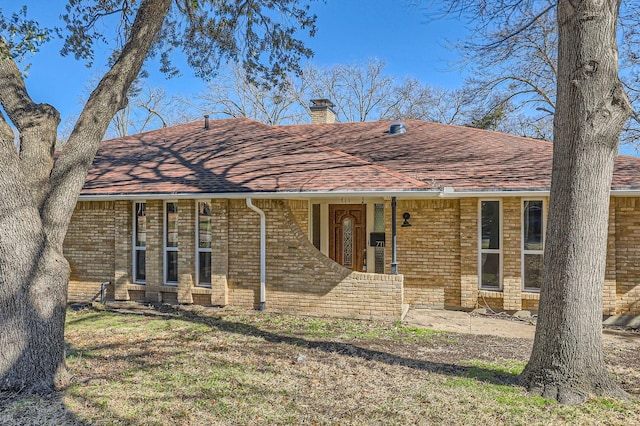 view of front facade featuring a shingled roof, a chimney, and brick siding