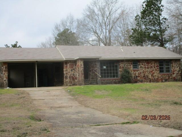 single story home featuring stone siding, driveway, and a front lawn