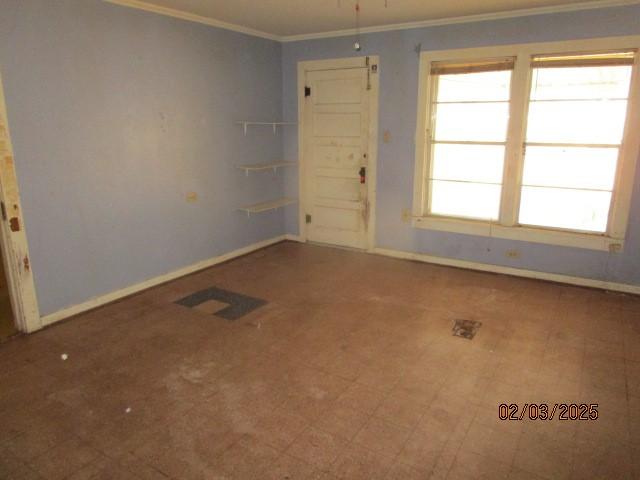 empty room featuring ornamental molding, tile patterned floors, and baseboards