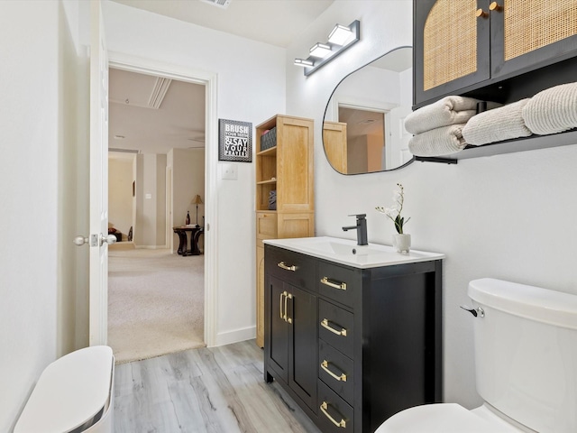 half bath with vanity, toilet, and wood finished floors