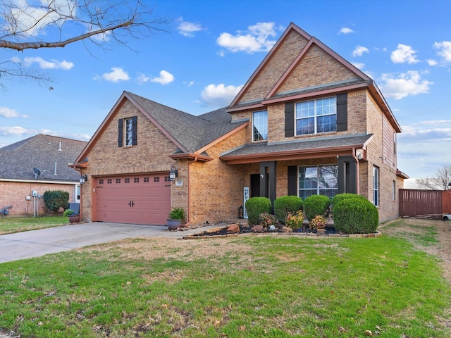 traditional-style home with brick siding, an attached garage, fence, driveway, and a front lawn