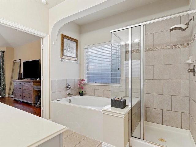 bathroom with a stall shower, tile patterned flooring, and a bath