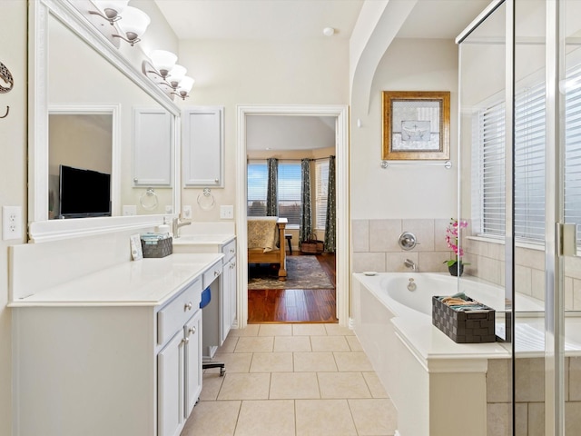 ensuite bathroom featuring a garden tub, ensuite bath, vanity, and tile patterned floors