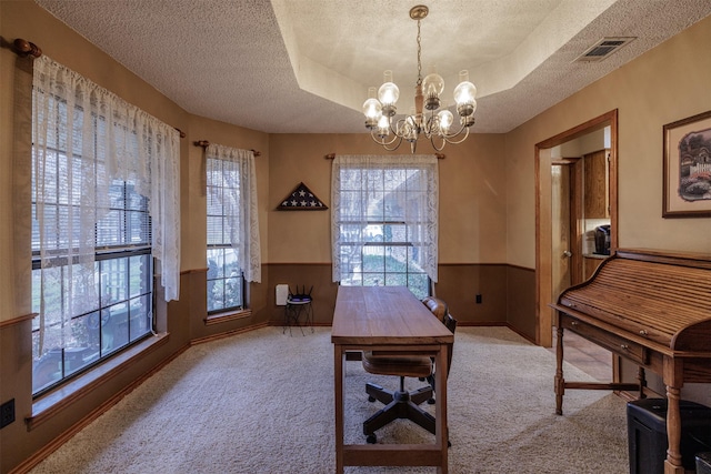 office space with a wainscoted wall, a tray ceiling, carpet, and visible vents