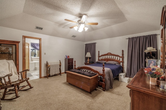 bedroom with light carpet, visible vents, a textured ceiling, and ensuite bathroom