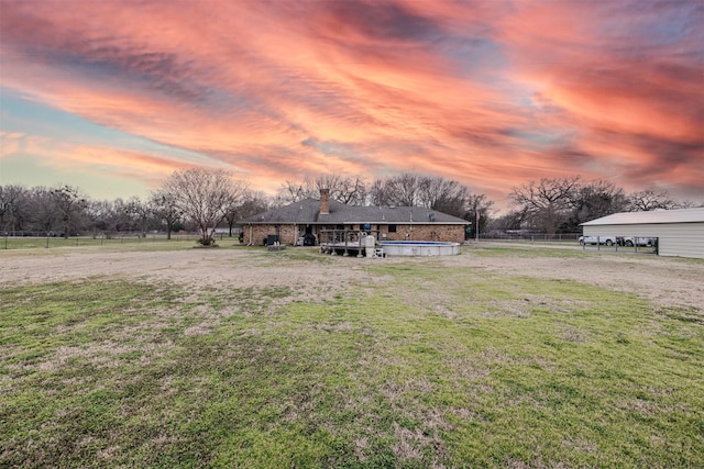 view of front facade featuring a rural view, fence, an outdoor pool, and a front yard