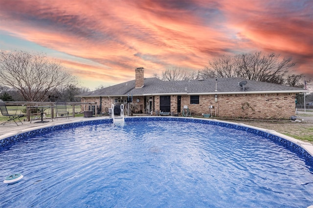 pool at dusk with a fenced in pool and fence