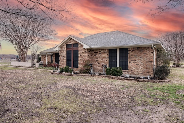 view of front of house with a shingled roof and brick siding