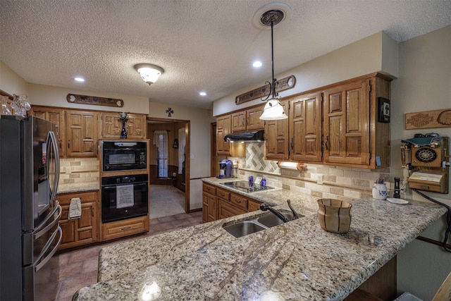 kitchen with black electric stovetop, under cabinet range hood, a peninsula, a sink, and freestanding refrigerator