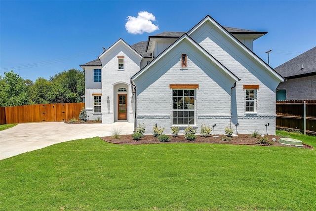 view of front of house featuring brick siding, fence, and a front lawn