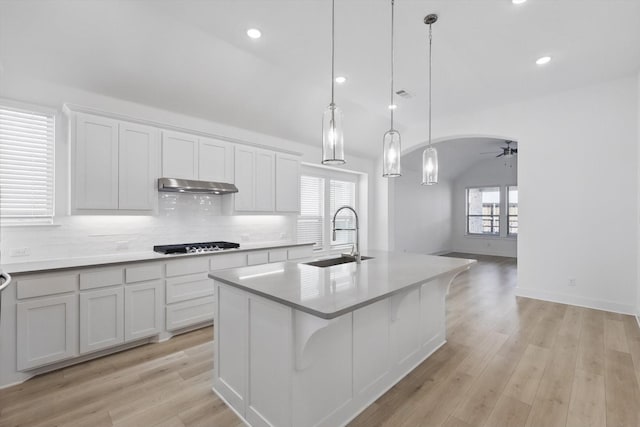 kitchen with tasteful backsplash, gas cooktop, under cabinet range hood, a sink, and ceiling fan