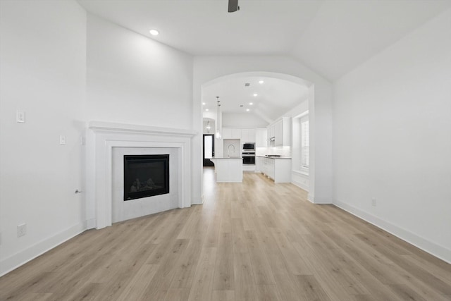 unfurnished living room with vaulted ceiling, recessed lighting, baseboards, light wood-style flooring, and a fireplace