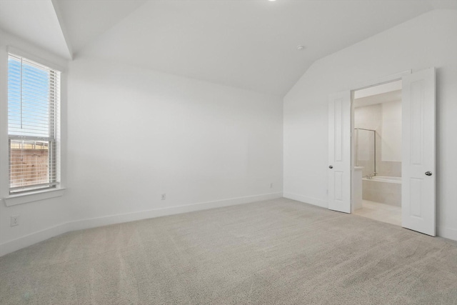 empty room featuring carpet, baseboards, and vaulted ceiling