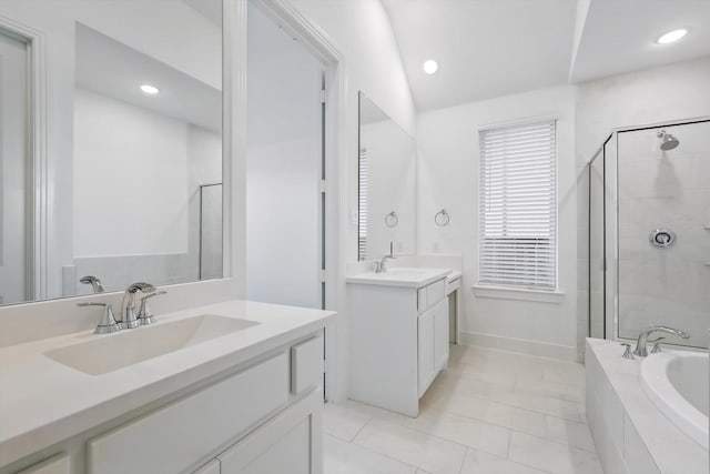 full bathroom featuring a stall shower, a garden tub, a sink, and two vanities