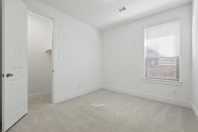 carpeted empty room featuring baseboards and visible vents