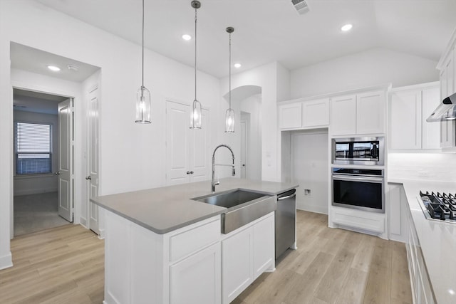 kitchen with a sink, white cabinetry, appliances with stainless steel finishes, lofted ceiling, and light wood-style flooring