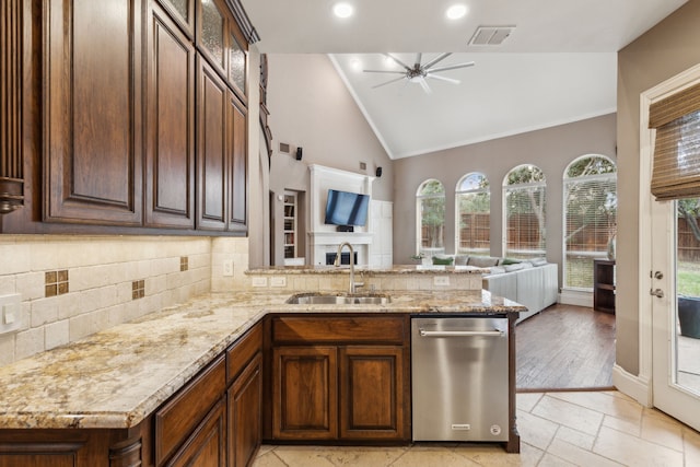 kitchen with decorative backsplash, open floor plan, a peninsula, a sink, and stainless steel dishwasher