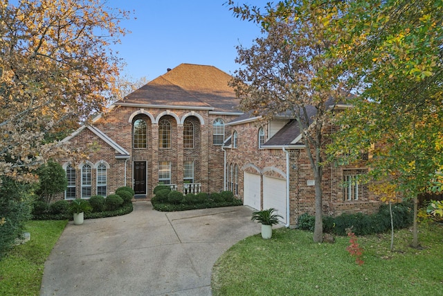 view of front facade featuring a garage, brick siding, a shingled roof, concrete driveway, and a front lawn