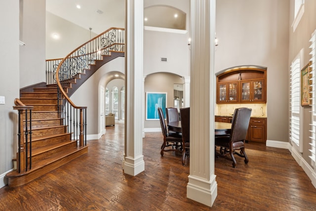 interior space featuring arched walkways, dark wood finished floors, decorative columns, visible vents, and baseboards