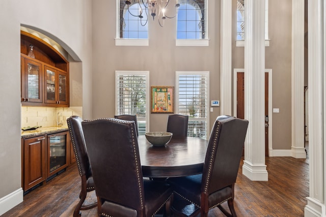 dining space with beverage cooler, an inviting chandelier, dark wood-style floors, and baseboards