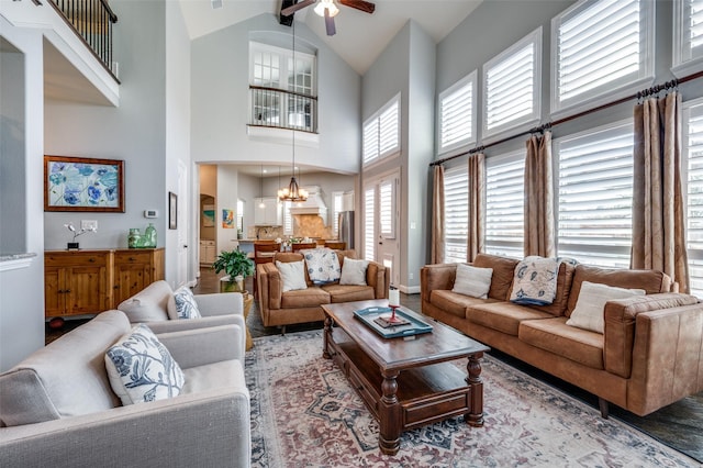 living room with vaulted ceiling, ceiling fan with notable chandelier, a wealth of natural light, and baseboards