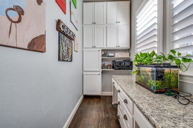 kitchen with dark wood-type flooring, white cabinetry, baseboards, light stone countertops, and open shelves