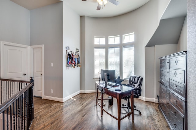 office space with a high ceiling, baseboards, and wood finished floors