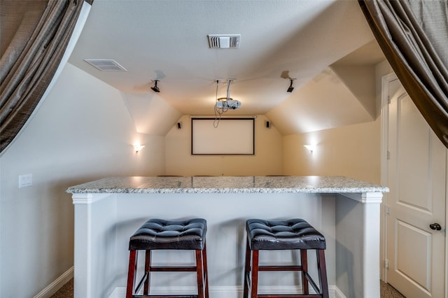 home theater featuring baseboards, visible vents, and vaulted ceiling