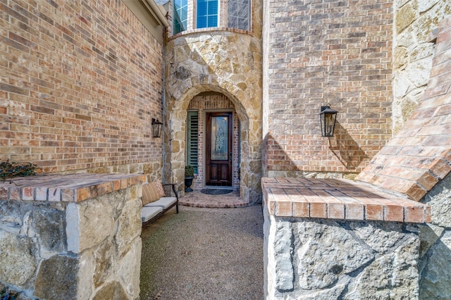 doorway to property featuring stone siding and brick siding