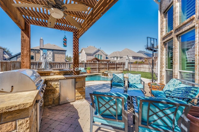 view of patio featuring a fenced backyard, a pool with connected hot tub, an outdoor kitchen, and a ceiling fan