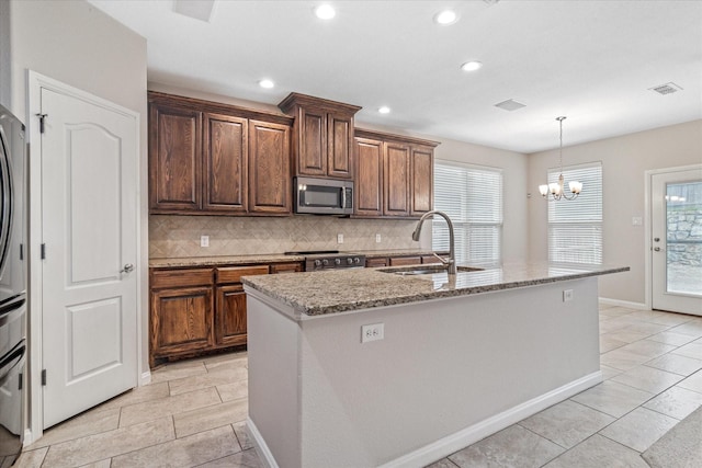 kitchen with appliances with stainless steel finishes, a sink, decorative backsplash, and light stone counters