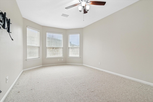 spare room featuring light carpet, ceiling fan, visible vents, and baseboards