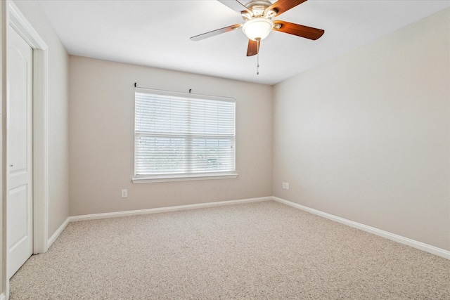 carpeted empty room featuring a ceiling fan and baseboards