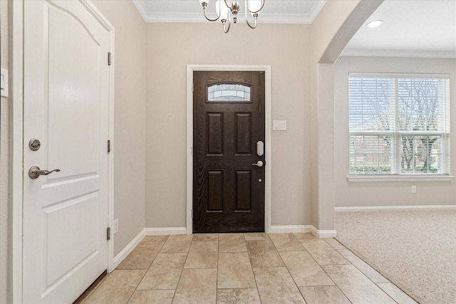 entrance foyer with an inviting chandelier, baseboards, arched walkways, and crown molding