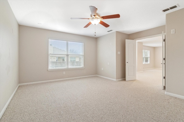 unfurnished room with visible vents, a wealth of natural light, and light colored carpet