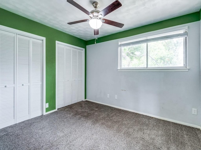 unfurnished bedroom with carpet, baseboards, and two closets