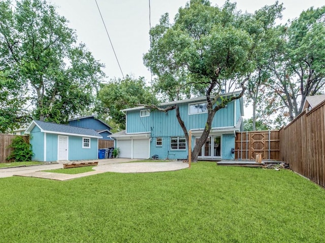 rear view of property featuring a yard, fence private yard, french doors, and driveway