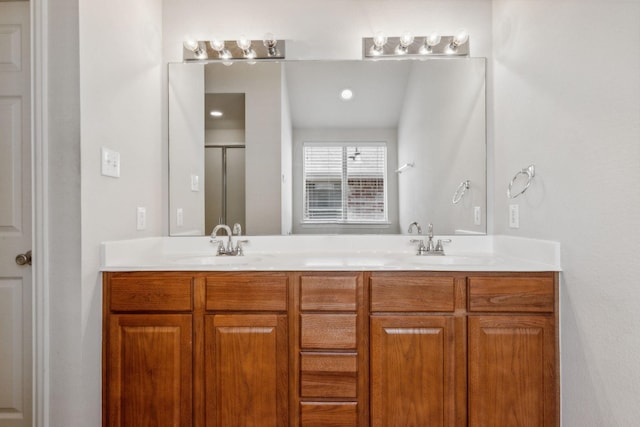 bathroom with double vanity, a stall shower, and a sink