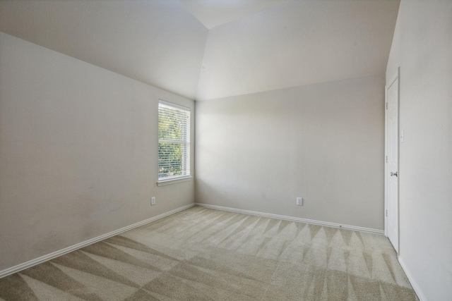 unfurnished room with vaulted ceiling, light carpet, and baseboards