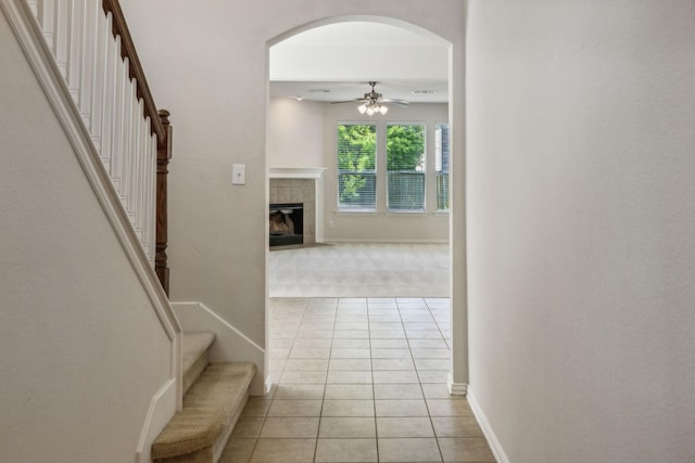 hallway with stairs, arched walkways, baseboards, and light tile patterned floors