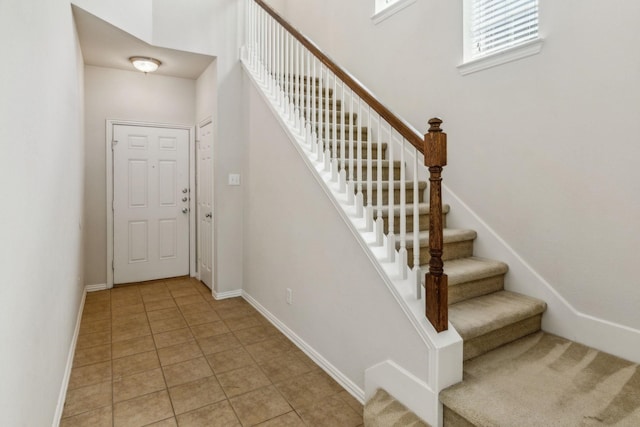 foyer entrance featuring light tile patterned floors, stairway, and baseboards