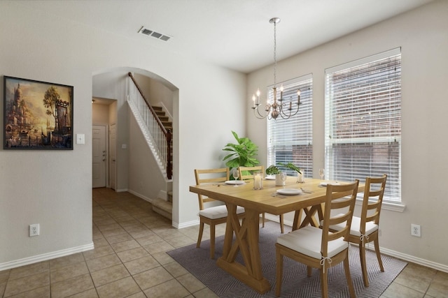 dining space with light tile patterned floors, arched walkways, visible vents, baseboards, and stairway