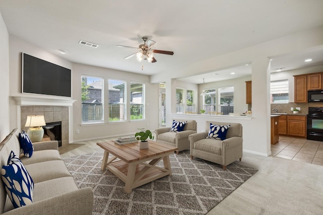 living room featuring plenty of natural light, a fireplace, visible vents, and a ceiling fan