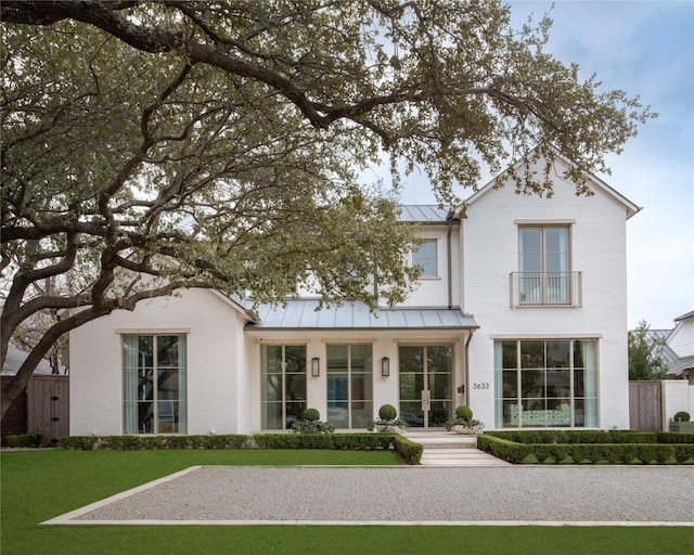 view of front of home featuring a front yard, a standing seam roof, brick siding, and metal roof