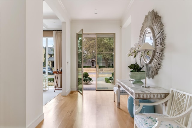 doorway to outside featuring ornamental molding, wood finished floors, and baseboards