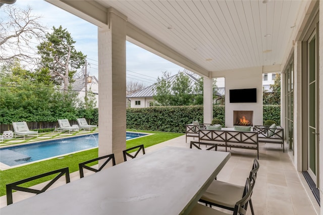 view of patio / terrace featuring an outdoor living space with a fireplace, outdoor dining space, a fenced backyard, and a fenced in pool