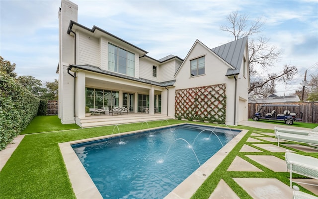 rear view of house featuring a fenced backyard, a chimney, metal roof, a standing seam roof, and a patio area