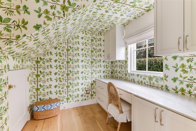 bathroom featuring wood finished floors and wallpapered walls