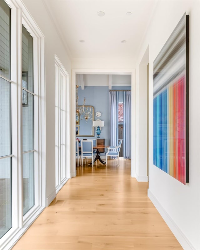 hall with light wood finished floors, baseboards, and ornamental molding